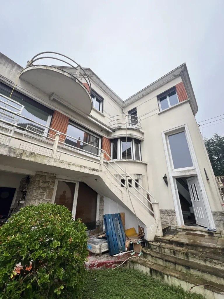 Maison moderne avec balcons et jardin.
